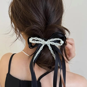 Elegant black satin bow hair tie with white pearls on woman's high ponytail