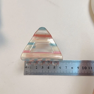 Dettaglio molletta per capelli triangolare in acetato a righe arcobaleno con scala di 6,5 cm