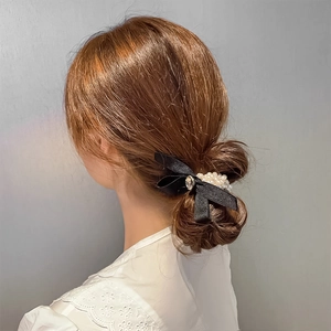 Eleganter Haargummi aus schwarzem Satin mit Perlenstreifen und Strass auf einem Dutt