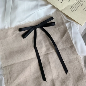 Elegante fermaglio per capelli in raso nero con fiocco e lunghi nastri su sfondo neutro