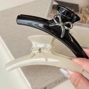 Détail de pinces à cheveux noires et crème avec nœuds 3D brillants et design élégant