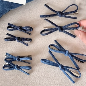 Blue denim bow hair clip set on a rustic fabric background with natural lighting