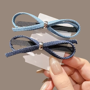 Set of light and dark blue denim bow hair clips with silver buckles on card display