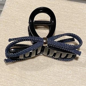 Detail of the blue denim bow with metallic ring on a black glossy hair claw clip