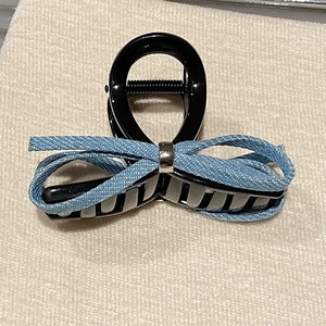 Close-up of denim fabric bow hair claw clip with silver metal ring and black plastic grip