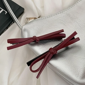 Macro detail of wine red faux leather bow hair clips on metallic background texture