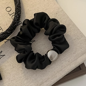Glossy black satin scrunchie featuring a polished silver metal bead on a fabric background