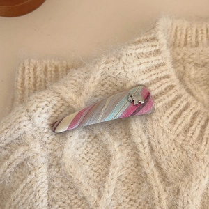 Rainbow plaid triangle hair clip with a silver dog ornament on a knit background