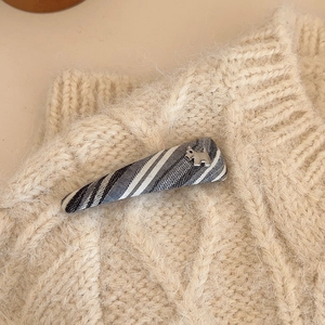 Retro checkered triangle BB hair clip with silver dog charm on a soft knit background