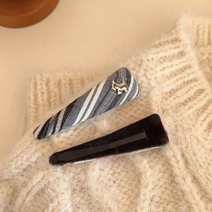 Vintage plaid triangle hair clips with silver puppy detail on warm knit background