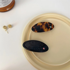 Macro detail of oval tortoiseshell and black hair clips with rhinestones in a tray