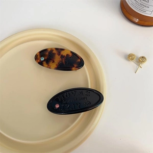 Oval tortoiseshell and black resin hair clips with embossed letters and crystal rhinestones