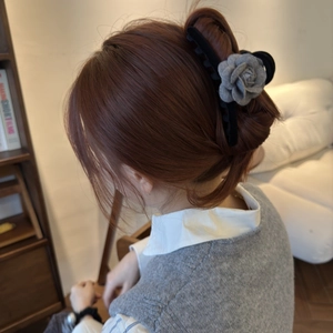 Pince à cheveux élégante avec camélia en tissu gris sur modèle dans un cadre doux