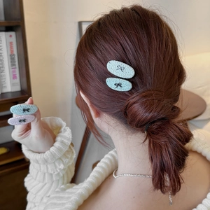 Elegant woven oval hair clip with metal bow accent in light green and pink tones