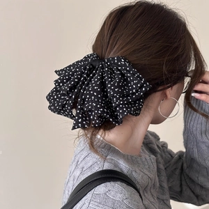 Detailed view of layered black polka dot organza bow hair clip on model's ponytail