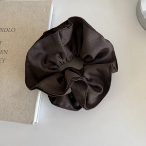 Solid deep coffee fabric scrunchie with pleated texture on a minimalist white surface