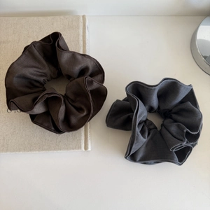 Detail of oversized fabric scrunchies in dark brown and charcoal grey textures