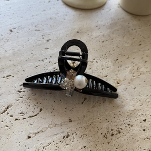 Elegant black hair claw clip featuring large white pearls and amber crystals on stone background