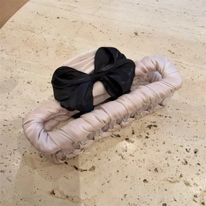 Elegante pinza de pelo grande en tela beige con lazo negro sobre mármol suave