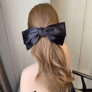 Détail d'une grande pince à cheveux en satin noir à double nœud sur le modèle