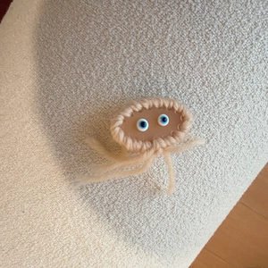 Cute handmade knitted jellyfish hair clip with brown resin body and pink yarn borders