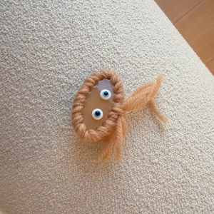 Handmade knitted hair clip featuring amber resin with blue evil eye beads on knit fabric