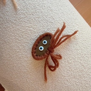 Detailed macro view of a handmade brown knitted crab hair clip with quirky blue eyes