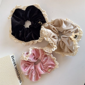 Three velvet hair scrunchies with lace edges in black, beige, and pink colors