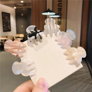 Close-up of six colorful acetate mini hair claws on a display card held by hand