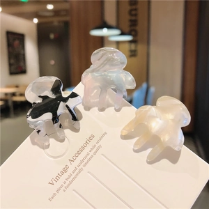 Three acetate mini hair claws in marble, pearlescent, and cream finish detail view