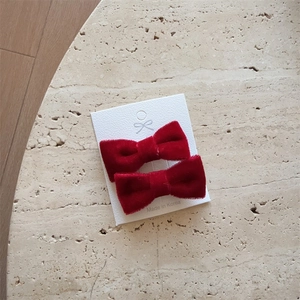 Elegant pair of deep red velvet bow hair clips displayed on a high-quality textured card
