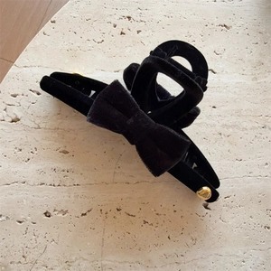 Detailed close-up of large black velvet bow hair claw clip with golden metal accents