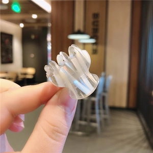 Close-up of a mini acetate hair claw clip with cream white and translucent stripes