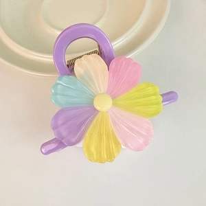 Détail d'une pince à cheveux fleur violette aux pétales arc-en-ciel sur plateau