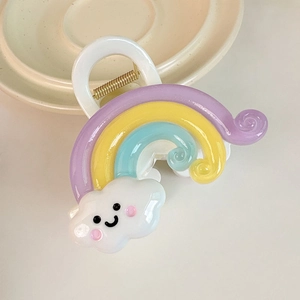 Détail d'une pince à cheveux nuage et arc-en-ciel en résine sur une assiette en céramique