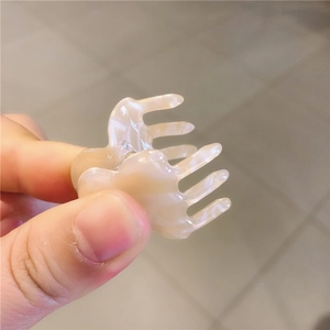 Close-up of mini cream marble acetate hair claw clip with multi-tooth design