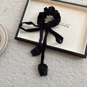 Detail of black velvet hair scrunchie with elegant ribbon and tulip bud charms