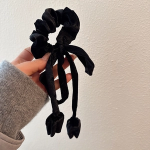 Detail view of the soft black velvet ribbon scrunchie featuring elegant hanging streamers