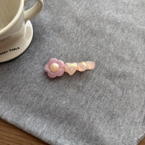 Dettaglio della clip per capelli a fiore in acrilico rosa con base in metallo dorato