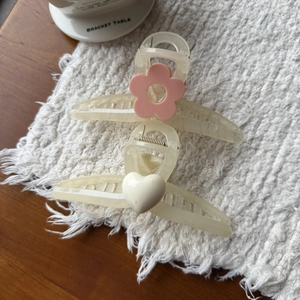 Detail van elegante haarklemmen van 13cm met roze bloemen en crème hartjes op matje