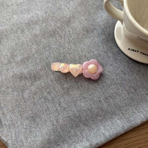 Fermagli per capelli a fiore in acrilico rosa e viola su sfondo in maglia grigia