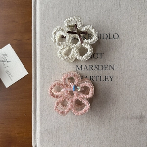 Detailed view of floral hair claws with pearl beads and ribbon bow accents
