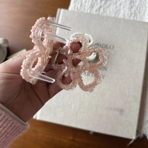 Close-up of a pink transparent flower hair claw clip with delicate pearl beads details