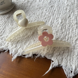 Detail van elegante haarklemmen van 13cm met hart en roze bloem op een zachte stoffen ondergrond