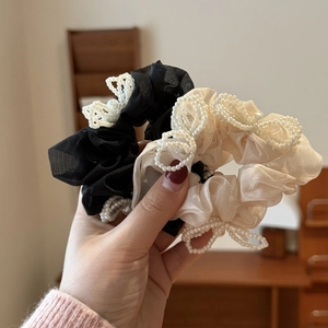 Detailed shot of mesh scrunchies with faux pearl bows in black and beige colors