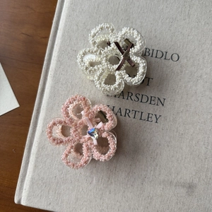 Detailed close-up of pearl beaded floral hair claws with bows on a vintage book