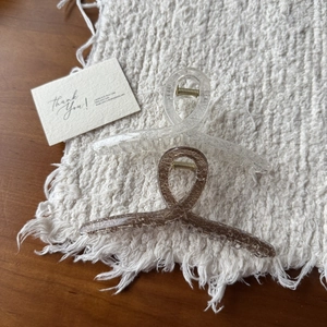 Detail view of two large hair claws with silver glitter and marble textures on a table