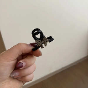 Detailed view of a mini black hair claw clip featuring a rhinestone bow design decoration