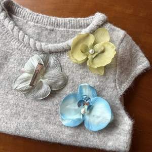 Detailed view of realistic orchid hair clips in blue, yellow, and white with pearl centers