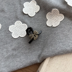 Detail of mini black hair claw with sparkling grey rhinestones on a knitted background